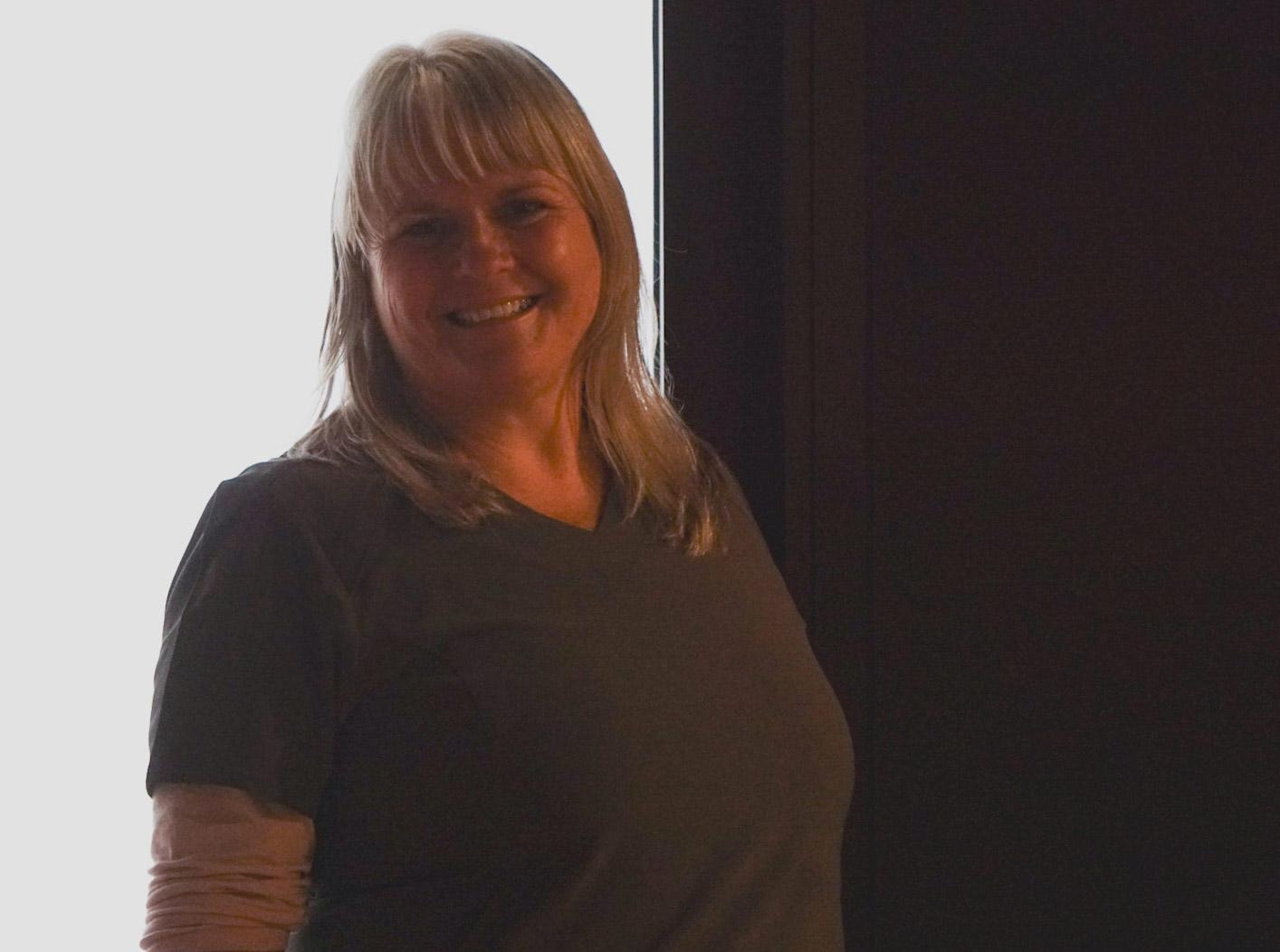 Susannah, founder of Deep Rest Studio, seated at the studio's live-edge timber table